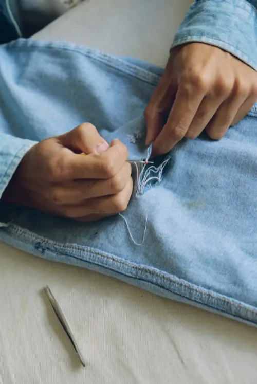Hands sewing or repairing jean pants