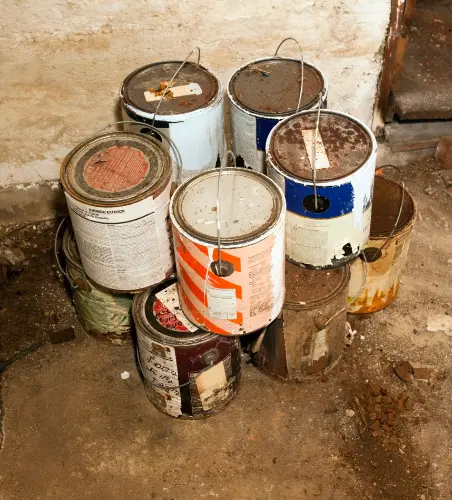 Rusty old paint cans stacked in garage, example of HHW