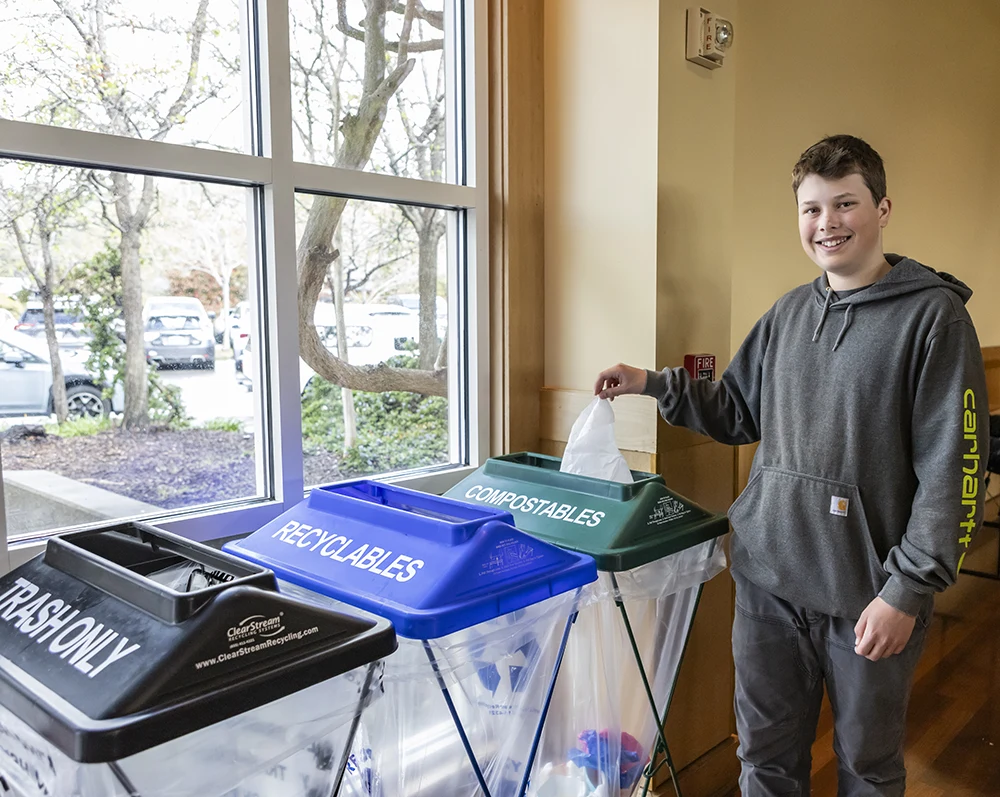 A boy smiles as he places a napkin in the compostables container at a Zero Waste Marin event