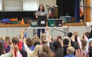 A Zero Waste Marin coordinator talks to a an assembly full of kids raising their hands in Marin County